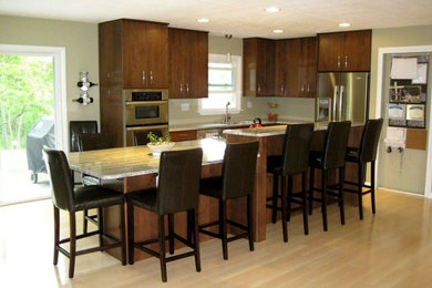 Open concept kitchen - large transitional l-shaped light wood floor and beige floor open concept kitchen idea in Atlanta with a double-bowl sink, flat-panel cabinets, dark wood cabinets, granite countertops, white backsplash, stainless steel appliances and an island