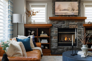 Transitional medium tone wood floor and brown floor living room photo in Calgary with a standard fireplace, a stone fireplace and a wall-mounted tv