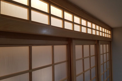 Diseño de dormitorio principal asiático grande con paredes blancas, suelo de bambú y suelo amarillo