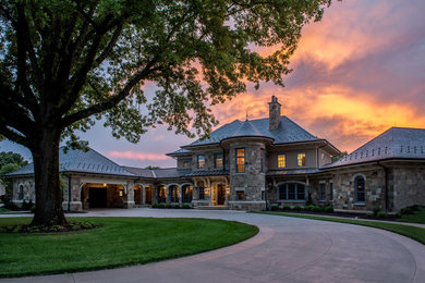 Huge traditional brown three-story stone exterior home idea in Other with a hip roof
