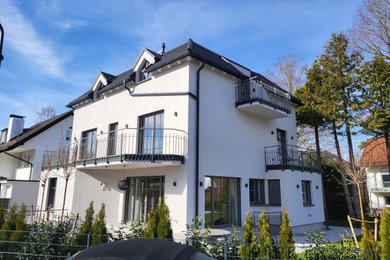 Ejemplo de fachada de casa gris y gris actual de tamaño medio con revestimiento de estuco, tejado a cuatro aguas y tejado de teja de barro