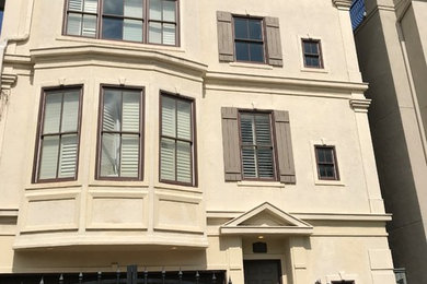 Large tuscan beige three-story stucco townhouse exterior photo in Houston with a tile roof