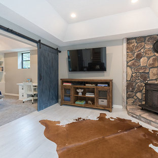 Design ideas for a large farmhouse look-out basement in Atlanta with blue walls, ceramic flooring, a wood burning stove, a stone fireplace surround and beige floors.