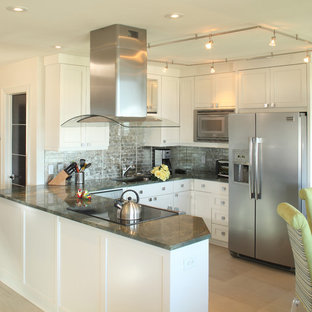 На фото: маленькая п-образная кухня в морском стиле с обеденным столом, накладной раковиной, фасадами с выступающей филенкой, белыми фасадами, столешницей из дерева, фартуком цвета металлик, фартуком из стеклянной плитки, техникой из нержавеющей стали, полом из цементной плитки, бежевым полом и серой столешницей без острова с