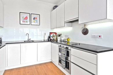 Inspiration for a medium sized modern u-shaped open plan kitchen in London with glass-front cabinets, white cabinets, marble worktops, white splashback and white appliances.