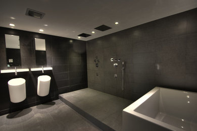Example of a minimalist master gray tile and ceramic tile bathroom design in Other with a wall-mount toilet and gray walls