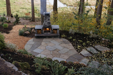 Example of a mid-sized mountain style stone patio design in Other with a fireplace
