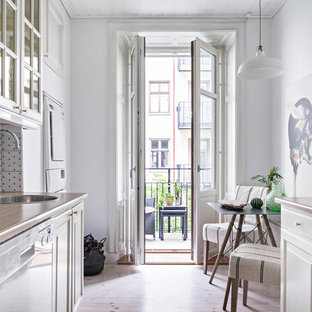 На фото: маленькая параллельная кухня в скандинавском стиле с обеденным столом, одинарной раковиной, фасадами с декоративным кантом, белыми фасадами, деревянной столешницей, разноцветным фартуком и светлым паркетным полом с