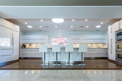 Inspiration for a contemporary galley concrete floor enclosed kitchen remodel in St Louis with an undermount sink, multicolored backsplash, paneled appliances, white cabinets and an island