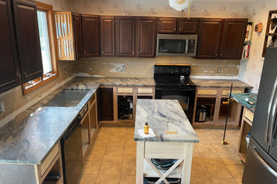 Mid-sized elegant l-shaped eat-in kitchen photo in Boston with an undermount sink, raised-panel cabinets, dark wood cabinets, quartzite countertops, ceramic backsplash, black appliances, an island and gray countertops