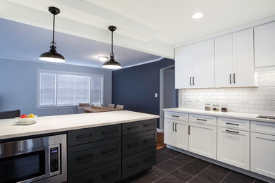 Black floor kitchen photo in Chicago with white backsplash, stainless steel appliances and white countertops