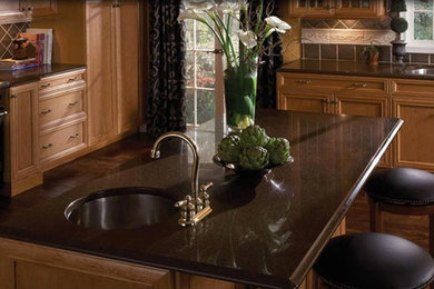 Inspiration for a medium tone wood floor kitchen remodel in Nashville with a single-bowl sink, medium tone wood cabinets, granite countertops, brown backsplash and an island