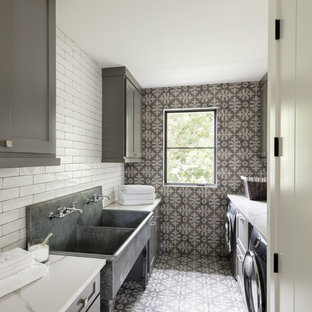 デンバーのカントリー風おしゃれな洗濯室 (スロップシンク、シェーカースタイル扉のキャビネット、グレーのキャビネット、左右配置の洗濯機・乾燥機、マルチカラーの床、白いキッチンカウンター、グレーの壁) の写真