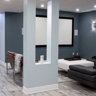 Photo of a large modern fully buried basement in Toronto with blue walls, laminate floors, a hanging fireplace, a tiled fireplace surround and grey floors.