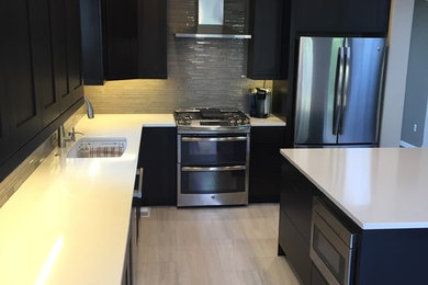 Inspiration for a large transitional l-shaped separate kitchen in Denver with an undermount sink, shaker cabinets, dark wood cabinets, solid surface benchtops, grey splashback, glass tile splashback, stainless steel appliances, laminate floors, with island and beige floor.