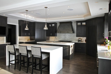 Example of a large trendy u-shaped dark wood floor and brown floor open concept kitchen design in Omaha with two islands, an undermount sink, flat-panel cabinets, dark wood cabinets, quartz countertops, metallic backsplash, matchstick tile backsplash and paneled appliances