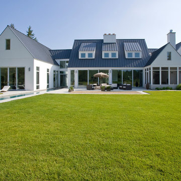 Rear Elevation of Contemporary European Farmhouse in White Stucco Metal Roof