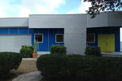 This is an example of a mid-sized transitional two-storey blue house exterior in Orlando with mixed siding and a flat roof.