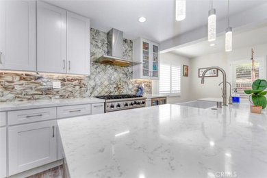 Kitchen - modern kitchen idea in Los Angeles with a drop-in sink, white cabinets, quartz countertops, beige backsplash, stainless steel appliances and white countertops