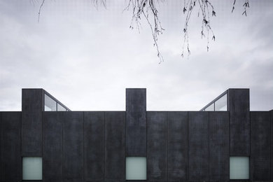 Modelo de fachada gris moderna grande de una planta con revestimiento de piedra y tejado plano