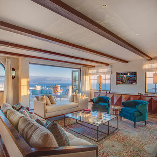 Ejemplo de salón cerrado, mediterráneo, grande, con paredes beige, suelo de madera en tonos medios, televisor colgado en la pared, chimenea de doble cara y marco de chimenea de yeso