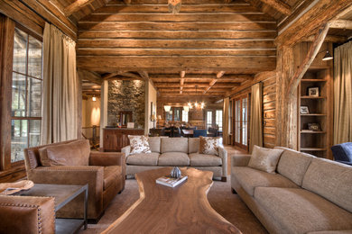 Photo of a large traditional open concept living room in Other with medium hardwood floors, a standard fireplace, a stone fireplace surround, a built-in media wall and brown walls.