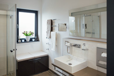 Großes Modernes Badezimmer En Suite mit flächenbündigen Schrankfronten, weißen Schränken, Einbaubadewanne, bodengleicher Dusche, Wandtoilette, weißen Fliesen, Porzellanfliesen, weißer Wandfarbe, Porzellan-Bodenfliesen, Aufsatzwaschbecken, Waschtisch aus Holz, schwarzem Boden und offener Dusche in Köln