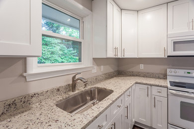 Mid-sized transitional u-shaped kitchen in DC Metro with an undermount sink, shaker cabinets, white cabinets, granite benchtops, white appliances, dark hardwood floors, no island, brown floor and multi-coloured benchtop.