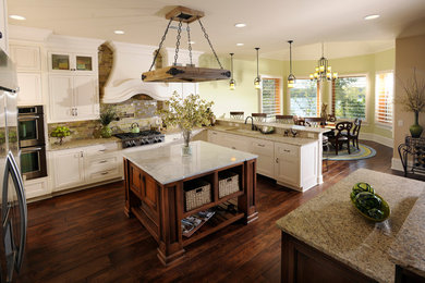 This is an example of a mid-sized traditional u-shaped separate kitchen in Nashville with a double-bowl sink, shaker cabinets, white cabinets, granite benchtops, multi-coloured splashback, glass tile splashback, stainless steel appliances, dark hardwood floors, with island and brown floor.