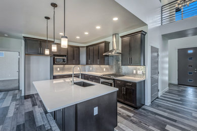 Open concept kitchen - mid-sized traditional l-shaped medium tone wood floor and gray floor open concept kitchen idea in Other with an undermount sink, flat-panel cabinets, dark wood cabinets, laminate countertops, gray backsplash, stainless steel appliances, an island and white countertops