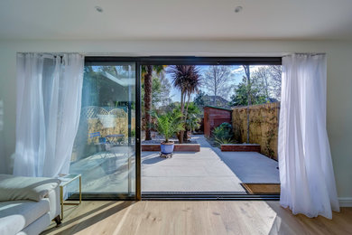 Modern open plan living room in London with white walls, light hardwood flooring and brown floors.