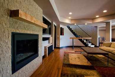 Huge trendy walk-out basement photo in Denver with a standard fireplace and a stone fireplace
