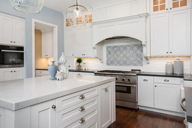 Example of a large transitional u-shaped dark wood floor and brown floor kitchen pantry design in Tampa with a farmhouse sink, shaker cabinets, white cabinets, soapstone countertops, white backsplash, subway tile backsplash, stainless steel appliances, an island and gray countertops