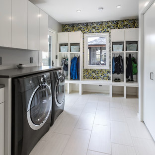 ミルウォーキーの大きいコンテンポラリースタイルのおしゃれな家事室 (フラットパネル扉のキャビネット、白いキャビネット、珪岩カウンター、グレーの壁、ラミネートの床、左右配置の洗濯機・乾燥機、白い床、グレーのキッチンカウンター) の写真
