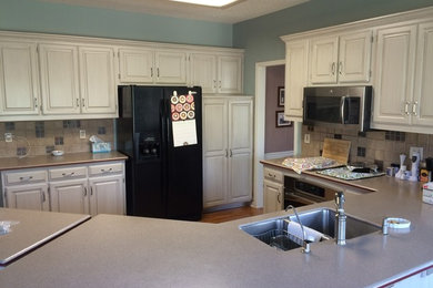 Example of a mid-sized trendy l-shaped dark wood floor enclosed kitchen design in Little Rock with raised-panel cabinets, gray cabinets, a double-bowl sink, laminate countertops, beige backsplash, stone tile backsplash, stainless steel appliances and a peninsula