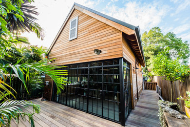 This is an example of a small contemporary two-storey house exterior in Sydney with wood siding, a gable roof and a metal roof.