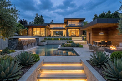 Design ideas for a large modern drought-tolerant and full sun backyard concrete paver and metal fence landscaping in Los Angeles with a fire pit for spring.