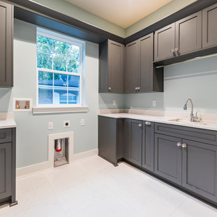ジャクソンビルの大きい地中海スタイルのおしゃれな家事室 (スロップシンク、シェーカースタイル扉のキャビネット、グレーのキャビネット、クオーツストーンカウンター、青い壁、磁器タイルの床、白い床、マルチカラーのキッチンカウンター、左右配置の洗濯機・乾燥機) の写真