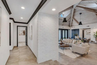 Example of a huge transitional travertine floor, beige floor and exposed beam entryway design in San Diego with white walls