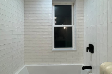 Imagen de cuarto de baño único de tamaño medio con bañera empotrada, baldosas y/o azulejos blancos, baldosas y/o azulejos de cemento y puertas de armario negras