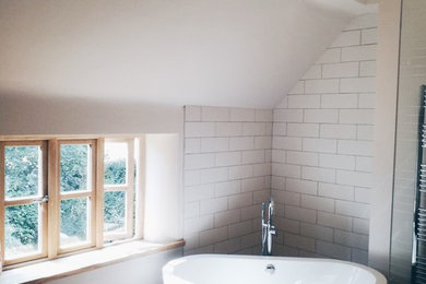 This is an example of a scandi family bathroom in Other with a freestanding bath, a walk-in shower, white tiles, dark hardwood flooring, a wall mounted toilet, white walls and a console sink.
