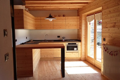 Mid-sized country l-shaped open plan kitchen in Turin with light hardwood floors and with island.