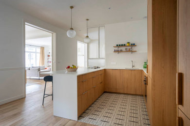 Inspiration pour une cuisine américaine encastrable, bicolore et blanche et bois design en U et bois clair de taille moyenne avec un évier 1 bac, un placard à porte affleurante, plan de travail en marbre, une crédence blanche, une crédence en céramique, un sol en carrelage de céramique, une péninsule, un sol multicolore et un plan de travail blanc.