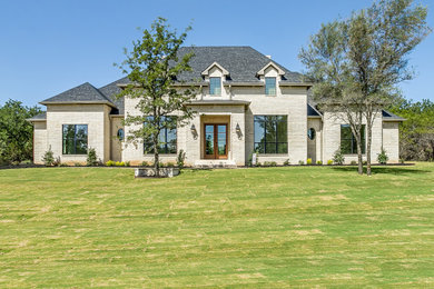 Inspiration for a large french country white one-story brick house exterior remodel in Dallas with a hip roof, a shingle roof and a black roof