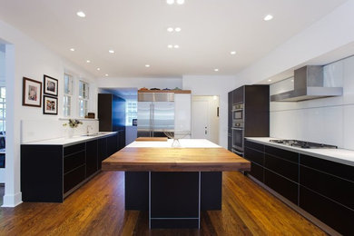 Inspiration for a mid-sized contemporary u-shaped medium tone wood floor kitchen pantry remodel in Chicago with a farmhouse sink, flat-panel cabinets, dark wood cabinets, solid surface countertops, glass sheet backsplash, stainless steel appliances and an island
