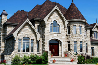 Mid-sized traditional two-storey grey house exterior in Orange County with stone veneer, a gable roof and a shingle roof.