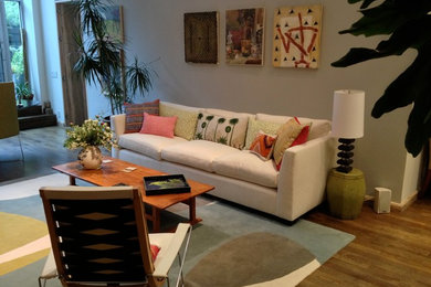 Example of a mid-sized trendy formal and open concept medium tone wood floor and brown floor living room design in New York with beige walls, no fireplace and no tv
