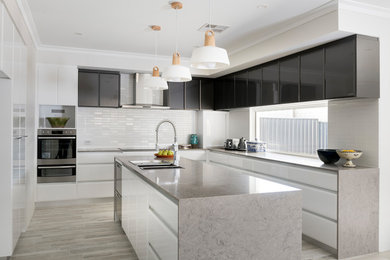 Modern u-shaped kitchen in Perth with an undermount sink, solid surface benchtops, white splashback, subway tile splashback, stainless steel appliances, porcelain floors, with island, grey floor and grey benchtop.