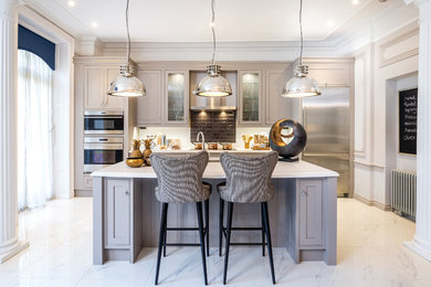 Photo of a classic kitchen in Other with glass-front cabinets, brown splashback, metro tiled splashback, stainless steel appliances, an island and grey cabinets.