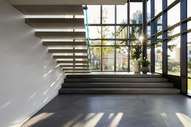 Imagen de escalera suspendida contemporánea con escalones con baldosas, contrahuellas con baldosas y/o azulejos y barandilla de varios materiales